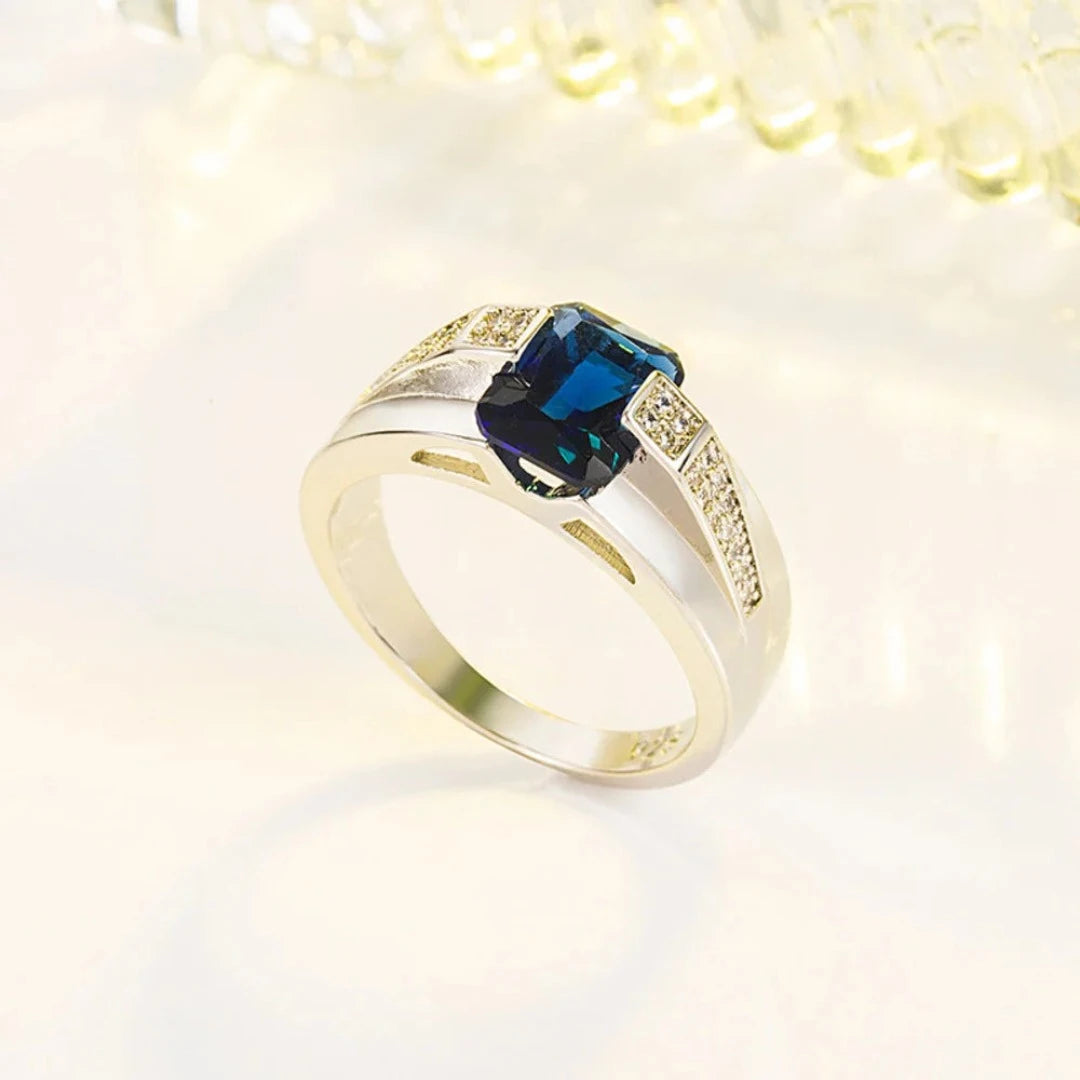 Fabricado com prata 925 de alta qualidade, este anel apresenta um acabamento polido que realça a beleza natural do metal precioso. O destaque indiscutível é a pedra azul central, que captura a luz de maneira fascinante, adicionando um toque de glamour e mistério à peça.
