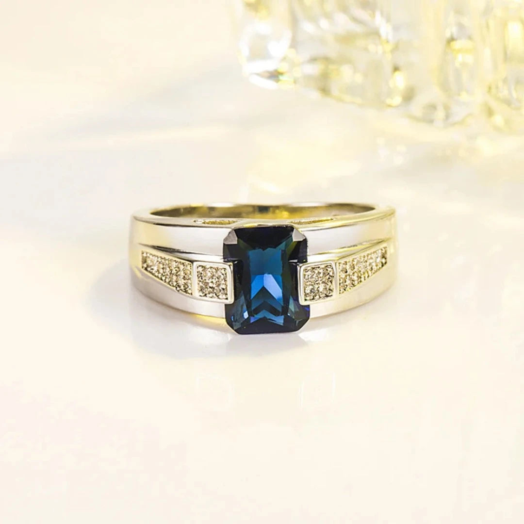 Fabricado com prata 925 de alta qualidade, este anel apresenta um acabamento polido que realça a beleza natural do metal precioso. O destaque indiscutível é a pedra azul central, que captura a luz de maneira fascinante, adicionando um toque de glamour e mistério à peça.