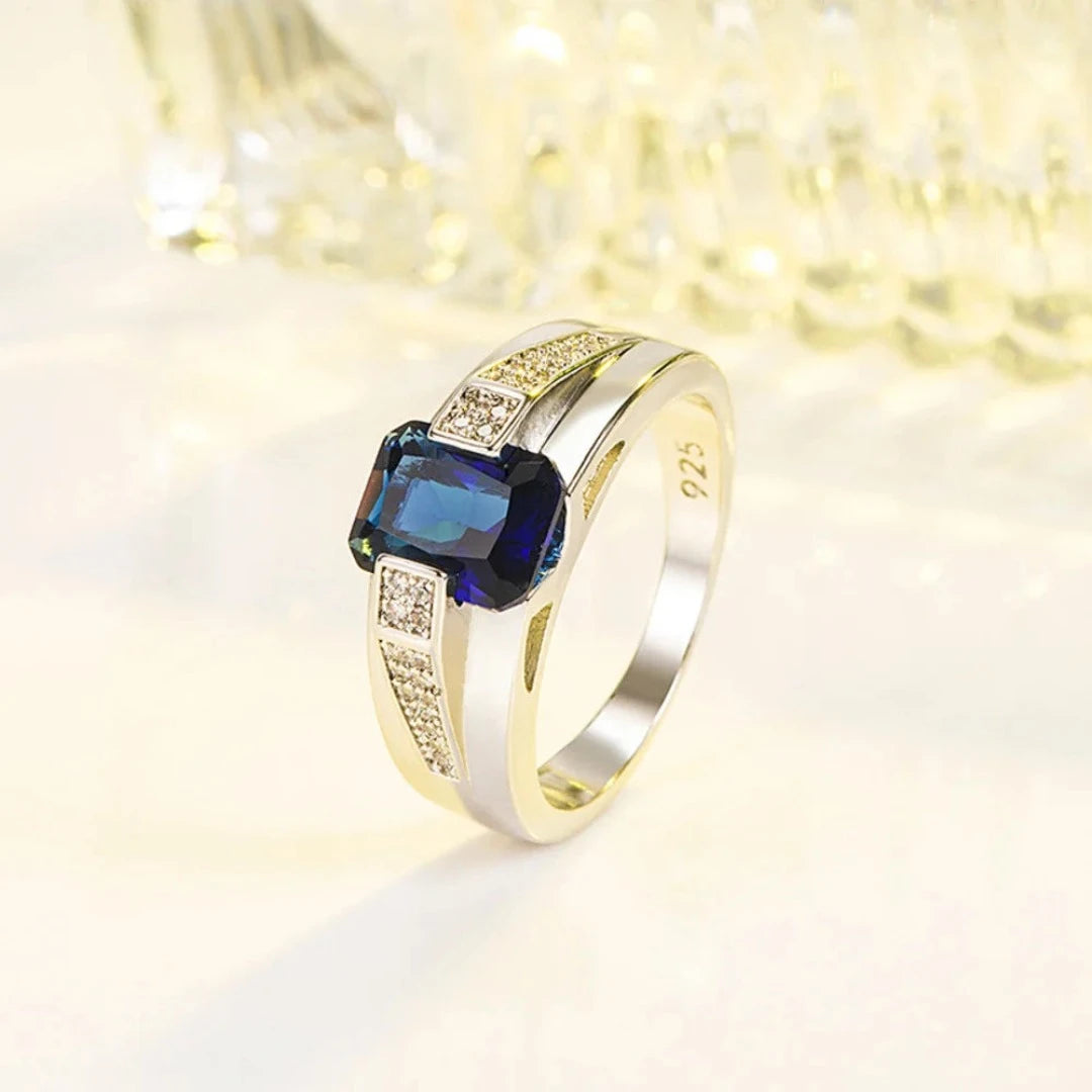 Fabricado com prata 925 de alta qualidade, este anel apresenta um acabamento polido que realça a beleza natural do metal precioso. O destaque indiscutível é a pedra azul central, que captura a luz de maneira fascinante, adicionando um toque de glamour e mistério à peça.